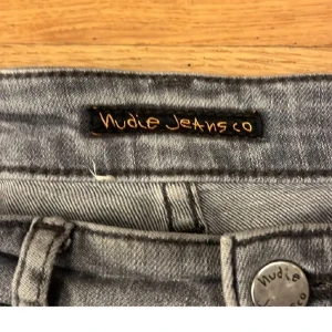 Nudie Jeans - Snygga grå jeans från Nudie Jeans med klassisk femficksdesign och broderade bakfickor. Jeansen har en rak passform och är tillverkade i mjukt denimtyg. Perfekta för dig som gillar en stilren och avslappnad look.