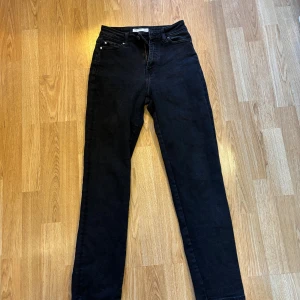 Svarta mom fit jeans XS/32 - Svarta mom fit jeans från Bik Bok i storlek XS/32. Klassisk femficksmodell med hög midja och raka ben. Jeansen har dragkedja och knapp framtill samt bälteshällor. Materialet är robust denim i svart ton, perfekt för en chill och stilren look. Passar även S. Väldigt stretchiga. 