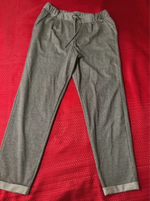 Grå linnebyxor från Esmara med snörning - Säljer ett par grå linnebyxor från Esmara med tunna vita ränder. Byxorna har elastisk midja med snörning och raka ben. Perfekta för chill dagar eller när du vill ha en avslappnad look. Fina att vika upp i bensluten för extra stil.