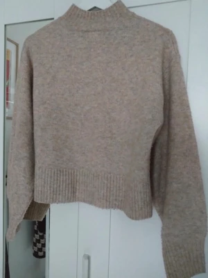 Beige stickad tröja från Monki - Mysig beige stickad tröja från Monki i storlek XS. Tröjan har hög hals, ribbade muddar. Inga defekter och varsamt använd