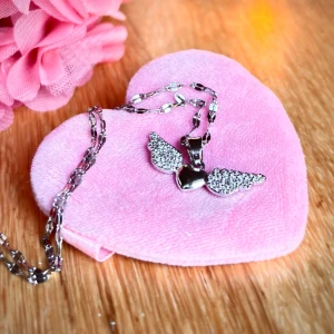 Fint halsband med hjärta och vingar! - Fint halsband i rostfritt stål med hjärta och vingar. Kedja medföljer. Mått hänge: 3 x 1,2 cm. Kedja: 50 cm. Nytt!