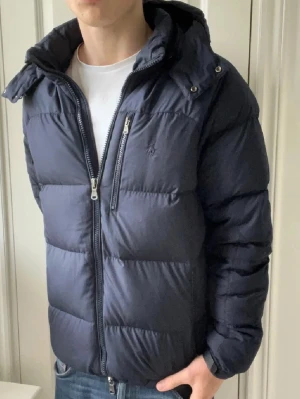 Ralph Lauren performance dun jacka  - Ralph Lauren performance dun jacka, en riktigt favorit hos oss. Extremt clean och tuff 😮‍💨. Den har väldigt bra passform och passar väldigt bra på modellen som är 180 cm 75 kg som bär Strlk S. Inga defekter på jackan ❣️denna är lite dyrare då den i våra ögon är några snäpp bättre än dom andra RL jackorna 😌färgen är lite marin blå / svart 