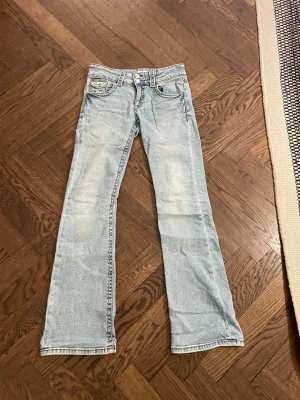 Gina tricot Ljusblåa bootcut jeans  - Säljer ett par ljusblå bootcut jeans med klassisk femficksmodell och normal passform från Gina tricot. Jeansen har låg midja och är tillverkade i mjukt denimtyg. Snygg tvättad look och raka ben som går ut lite nedtill för en retro vibe.I storlek 164