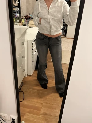 Grå bootcut jeans med låg midja - Säljer ett par grå jeans med bootcut-modell och låg midja. Jeansen har snygga detaljer på bakfickorna. Jätte snygg tvätt på dom här!