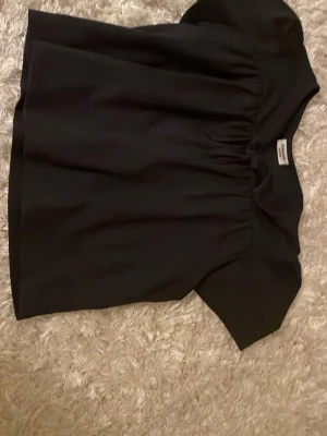 Marin blå blus från Kappahl - Säljer en marinblå blus från Kappahl i storlek 134/140. Blusen har korta ärmar, rund halsringning och lätt rynkade detaljer framtill som ger en snygg siluett. Perfekt att styla med jeans eller kjol för en clean look.