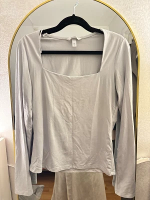 Ljusgrå/vit långärmad topp med fyrkantig ringning - En stilren ljusgrå långärmad topp från H&M med fyrkantig ringning. Tillverkad i mjuk bomullsmix som känns skön mot huden. Perfekt att matcha med jeans eller kjol för en clean look.