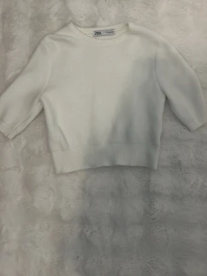 Vit stickad tröja från Zara - Mysig vit stickad tröja från Zara med rund halsringning och halvlånga ärmar. Tröjan har ribbade muddar i nederkant och vid ärmslut, vilket ger en clean och enkel look. Perfekt att styla med jeans eller kjol. Inga defekter och säljer då den tyvärr blivit för liten. 💗