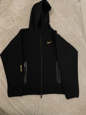 Nike Tech Fleece zip hoodie / Nocta - Nike Tech Fleece zip hoodie (Nike Trail) Stilren och funktionell hoodie i mjukt Tech Fleece-material. Lätt men varm, med huva, hel dragkedja och två dragkedjefickor. Perfekt för vardag, träning eller utomhusbruk. Mycket fint skick.