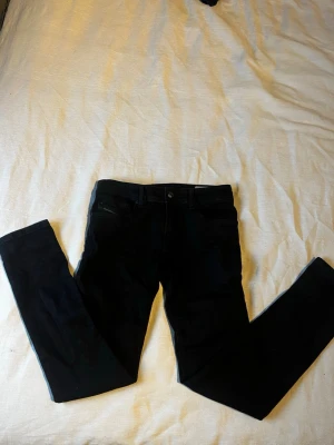 Svarta Diesel Sleenker skinny jeans - Säljer ett par svarta Diesel Sleenker-J-N jeans i slim-skinny modell. Jeansen har klassisk femficksdesign, stretchigt material och diskret Diesel Industry-detalj på fickan. Perfekta för dig som gillar en tajtare passform och stilren look. Helt oanvända! Storleken kan omvandlas UNGEFÄRLIGT till 28/30, skriv vid frågor😀