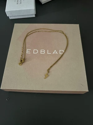 Edblad halsband - Edblad halsband i guld med en liten blixt på 
