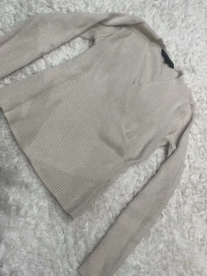 Beige sött omlopps tröja - En beige omlopps tröja som tyvärr har 2 fläckar på sig(ser på bilden).  det tidigare har varit en guldig sak på tröjan som trillade av och därmed lämnade ett litet hål som man oxå ser på bilden men annars är tröjan bra skick