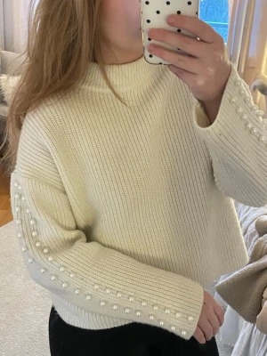 Vit stickad tröja med pärlor H&M - Superfin vit stickad tröja från H&M med pärldetaljer längs ärmarna. Saknar en pärla men lätt att fixa