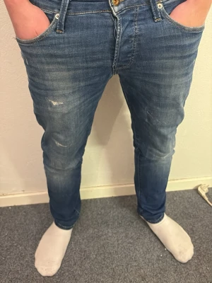 Slim Glenn Jack&jones jeans - Säljer ett slim glenn jack&jones jeans i klassisk blå tvätt med snygga slitningar och smal passform. Jeansen har fem fickor, normal midja och är tillverkade i mjukt jeansmaterial med lite stretch. Perfekta för dig som gillar en modern och stilren look. Modellen är 177cm väger 65