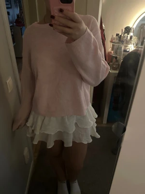 Vit volangkjol med resårmidja - Supersöt vit kortkjol med flera lager volanger och bred smock i midjan. Kjolen är gjord i ett lätt och luftigt tyg som ger en flowy känsla. Perfekt för dig som gillar en feminin och trendig stil. Passar till både sneakers och sandaler. 