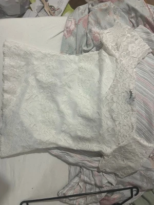 Vit spetsblus från new Yorker  - Säljer en superfin vit blus från Amisu i storlek S. Toppen är täckt av blommig spets och har offshoulder-modell med korta ärmar. Perfekt för dig som gillar romantisk och feminin stil. Materialet är mjukt och följsamt.