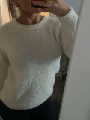 Slutsåld Vit fluffig stickad tröja 157 New - Mysig vit stickad tröja från 157 New med fluffig yta och rund hals. Tröjan har lång ärm och ribbade muddar vid hals, ärmslut och nederkant. Perfekt för dig som gillar en enkel men ändå stylish look. Passar som S/xs