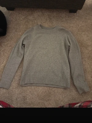 Grå stickad tröja i kashmir - Mysig grå stickad tröja i kashmir med rund hals och ribbade muddar vid ärmslut och nederkant. Perfekt för kyliga dagar och enkel att matcha med allt. Klassisk och stilren design som funkar till det mesta.