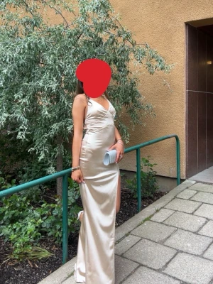 Champagnefärgad balklänning  - Säljer en elegant balklänning i champagnefärgad med smala axelband och v-ringning. Klänningen har en hög slits på sidan och ser ganska ny ut. Perfekt för bal eller festliga tillfällen.