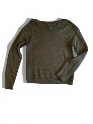 Mörkgrön stickad tröja - En enkel och stilren mörkgrön stickad tröja med bred ribbad kant vid halsen. Tröjan har lång ärm och rak passform, perfekt för lager på lager under kyliga dagar. Materialet känns mjukt och bekvämt mot huden. 