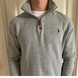 Grå half zip tröja från Polo Ralph Lauren - Snygg grå långärmad tröja från Polo Ralph Lauren med half zip och klassisk krage. Tröjan har ett broderat blått Polo-logo på bröstet och är gjord i mjuk bomull. Perfekt för chill dagar och enkel att matcha med jeans eller sweatpants. Nypris 2399kr! Använd fåtal gånger.