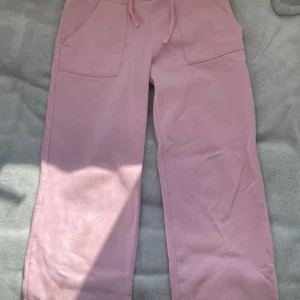 Ljusrosa mjukisbyxor med snörning - Supermysiga ljusrosa mjukisbyxor med bred resår i midjan och snörning framtill. Byxorna har raka ben, stora fickor både fram och bak och är perfekta för chill dagar. Tillverkade i mjukt bomullsmaterial för extra komfort.