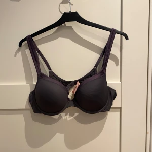Mörklila BH från Hunkemöller 80B - Säljer en stilren mörklila BH från Hunkemöller i storlek 80B. Den har vadderade kupor, justerbara axelband och klassisk bygel för extra stöd. Materialet är mjukt och lent mot huden, perfekt för dig som vill ha en bekväm och snygg bas i garderoben.