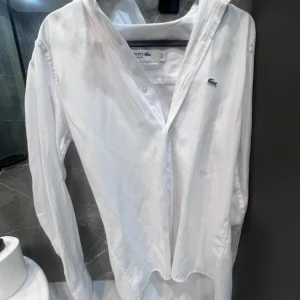 Lacoste skjorta - Helt ny Lacoste skjorta som jag säljer! Användes 1 gång till ett lugnt och fint bröllop, inga defekter, bra material, slim fit och så passar den till en person med storlek S, BUDGIVNING!!