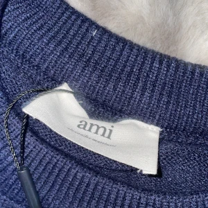 Mörkblå stickad tröja från Ami - Mörkblå stickad tröja från Ami med rund halsringning och lång ärm. På bröstet finns ett vitt hjärta med bokstaven A, vilket ger en unik och trendig look. Perfekt för dig som gillar stilrena men ändå lekfulla detaljer. Säljer den för köpte S istället för M