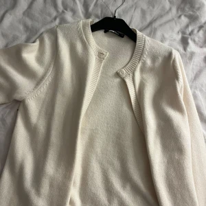 Cremefärgad kofta  - Superfin cremefärgad kofta från Gina Tricot med rund halsringning och knapp upptill. Mjuk och skön, perfekt att slänga över en topp. Klassisk och enkel design som funkar till allt. Storlek XS aldrig använd, helt ny 💕💕