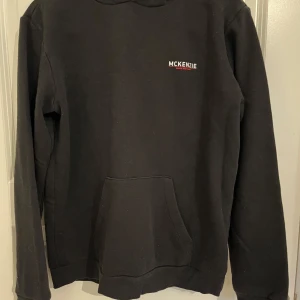 Svart hoodie från McKenzie XL - Svart hoodie från McKenzie med liten logga på bröstet. Klassisk känguruficka framtill och huva. Perfekt för chill dagar eller när du vill ha en enkel och stilren look. Mjuk insida och långärmad modell. Storlek XL för barn. Passar M oxå. 