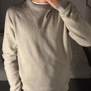 Beige stickad tröja från Mango - Säljer en stilren beige stickad från Mango. Den är i väldigt bra skick, man ser knabbt att den är använd bara lite smått tvättad. Modellen på bild är 174 63kg.