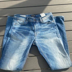 Jack & Jones Slim Fit Glenn jeans 30/30 - Snygga ljusblå slim fit jeans från Jack & Jones, modell Glenn. Jeansen har klassisk femficksdesign, normal midja och slitna detaljer framtill och baktill för en cool look. Tillverkade i mjukt denimtyg som sitter skönt hela dagen.