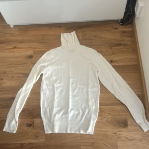 Vit polotröja från H&M XS - Klassisk vit polotröja från H&M i storlek XS. Tröjan har lång ärm och hög polokrage, perfekt för lager på lager. Tillverkad i mjukt material som känns skönt mot huden och passar till många olika outfits.