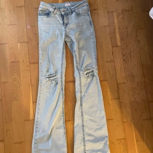 Bootcut jeans i ljus denim från Nelly - Bootcut jeans från Nelly i ljusblå denim med slitna knän och broderade bakfickor. Klassisk femficksmodell med normal passform och dragkedjegylf. Perfekta för dig som gillar en avslappnad och trendig look. Endast testade 