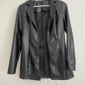 Svart skinnkavaj med knapp - Snygg svart kavaj i skinnimitation Materialet är mjukt