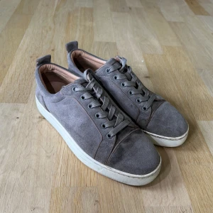Grå mockasneakers Christian Louboutin  - Christian Louboutin i bra skick 38 lite stor i storleken.  Inte mycket använda matchar till  mycket outfits . En liten fläck som syns på ena bilden men annars bra skick 👍