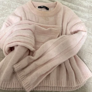 Ljusrosa stickad tröja FB Sister - Supermysig ljusrosa stickad tröja från FB Sister i storlek S. Tröjan har ett ribbat mönster, rund hals och långa ärmar med lite loose passform. Perfekt för kyliga dagar och enkel att matcha med jeans eller kjol. Snygg och enkel design som ger en soft vibe.