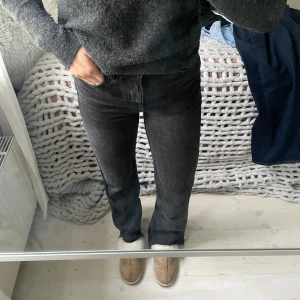 Svarta jeans från Zara  - Säljer ett par mörkgrå/svarta jeans med rak modell och rå, fransad kant nertill. Jeansen har hög midja och en liten slitning på högra bakfickan. 