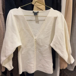 Vit blus  - Säljer denna jättefina vita blus från Lindex med djup v-ringning och knappar framtill. Blusen har trekvartsärmar med lite lätt puff. Använd endast ett fåtal gånger. Hör av dig om frågar eller bilder.