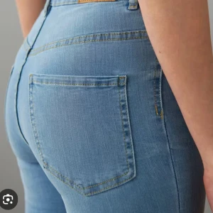 Ljusblå bootcut jeans med hög midja - Snygga ljusblå jeans med bootcut-ben och klassisk femficksdesign. Jeansen har hög midja och är tillverkade i mjukt denimtyg som sitter skönt. Perfekta för dig som gillar en retroinspirerad look med utsvängda ben.