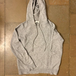 Grå hoodie i ull från Tiger of Sweden - Mjuk och stilren grå hoodie från Tiger of Sweden i 100% ull. Klassisk modell med huva och snörning, ribbade muddar och lång ärm. Perfekt för dig som gillar en clean och enkel look med premiumkänsla. Den har krympt lite i tvätten, sitter som S. //Victor 😇✌️