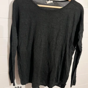 Mörkgrå långärmad tröja från H&M - En enkel och stilren mörkgrå långärmad tröja från H&M. Tröjan har rund halsringning och är tillverkad i mjuk bomullsmix, perfekt för lager-på-lager eller chill dagar. Passar dig som gillar basic och minimalistisk stil.