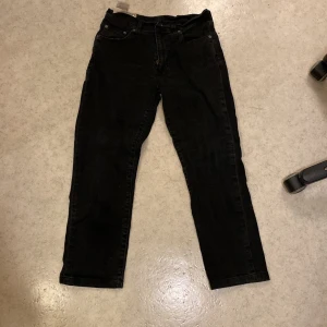 Svarta Levi's jeans straight fit - Svarta jeans från Levi's med klassisk femficksdesign och rakt ben. Jeansen har en enkel look med diskreta sömmar och den ikoniska röda Levi's-taggen på bakfickan. Perfekta för dig som gillar en clean och tidlös stil.