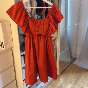 Röd volangklänning från Malina - Superfin röd klänning från Malina med volangärmar och plisserad överdel. Klänningen har en vacker, luftig form och är tillverkad i ett glansigt material som känns lyxigt. Perfekt för dig som vill sticka ut med en färgstark look. Använd en gång och efter det kemtvättad så den är som ny! SLUTSÅLD 2600 nypris! Skickar i kartongen den kom i
