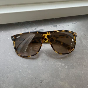 Ray-Ban Wayfarer leopardmönstrade solglasögon - Snygga Ray-Ban Wayfarer solglasögon med leopardmönstrad båge i brunt och gult. Glasen är bruna och ger en cool vintagekänsla. Perfekt accessoar för att lyfta din stil och skydda ögonen mot solen.