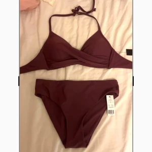 Vinröd bikini  - Supersnygg vinröd bikini från Missya, modell Aaliyah. Överdelen har omlott-design och smala axelband med knyt i nacken. Underdelen är klassisk tai-modell. Perfekt för stranden eller poolen, riktigt trendig färg och stilren look.