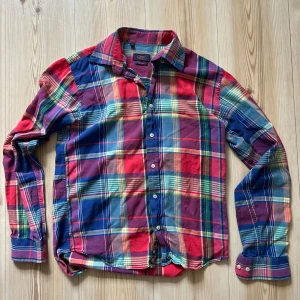 Rutig färgglad skjorta från Oscar - S - Färgstark rutig skjorta från Oscar i slim fit-modell. Skjortan har långa ärmar, klassisk krage och knäppning framtill. Mönstret är en mix av blått, rött, lila, grönt och gult. Tillverkad i mjuk bomull som känns skön mot huden.