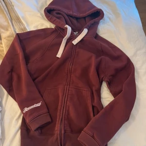 Vinröd hoodie från Russedress M - Mysig vinröd hoodie från Russedress med vit snörning i huvan och dragkedja. inga defekter!