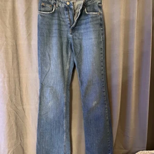 Blå raka jeans från ginatricot - Klassiska blå jeans från ginatricot i bootcut modell. Jeansen har fem fickor, normalhög midja och stängs med dragkedja och knapp. Materialet är robust denim i bomull. Perfekta för en avslappnad och tidlös look. Små hål på knäna