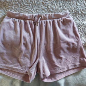 Rosa shorts från Juicy Couture - Ljusrosa shorts från Juicy Couture med snörning i midjan och en bakficka + ficka i sidorna. Använder 1 gång och är i bra skick. Men tyvärr lite tvätt skada. Sitter som storlek S men även XS, men funkar även som M. 